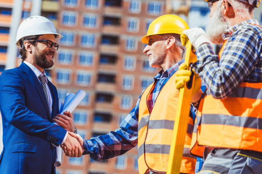 Two construction workers shaking hands at a building site.